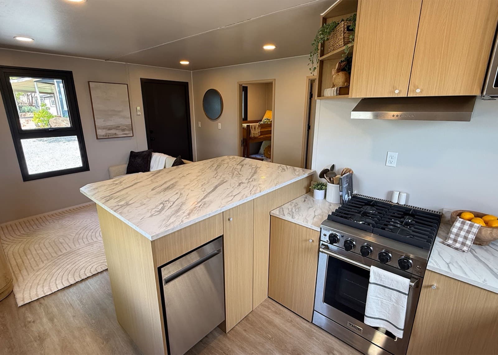Full kitchen with a gas range, island, and open living area beyond it in a BoxHouse Bungalow 2BR home