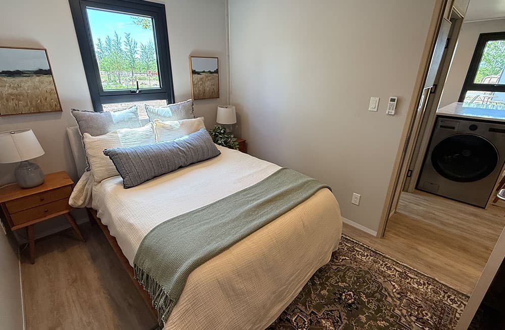 Private bedroom with a door and an in-unit washer and dryer beyond it