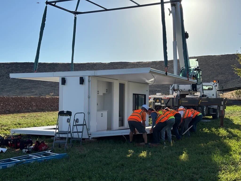 Crew installing a factory-built home on site with a crane