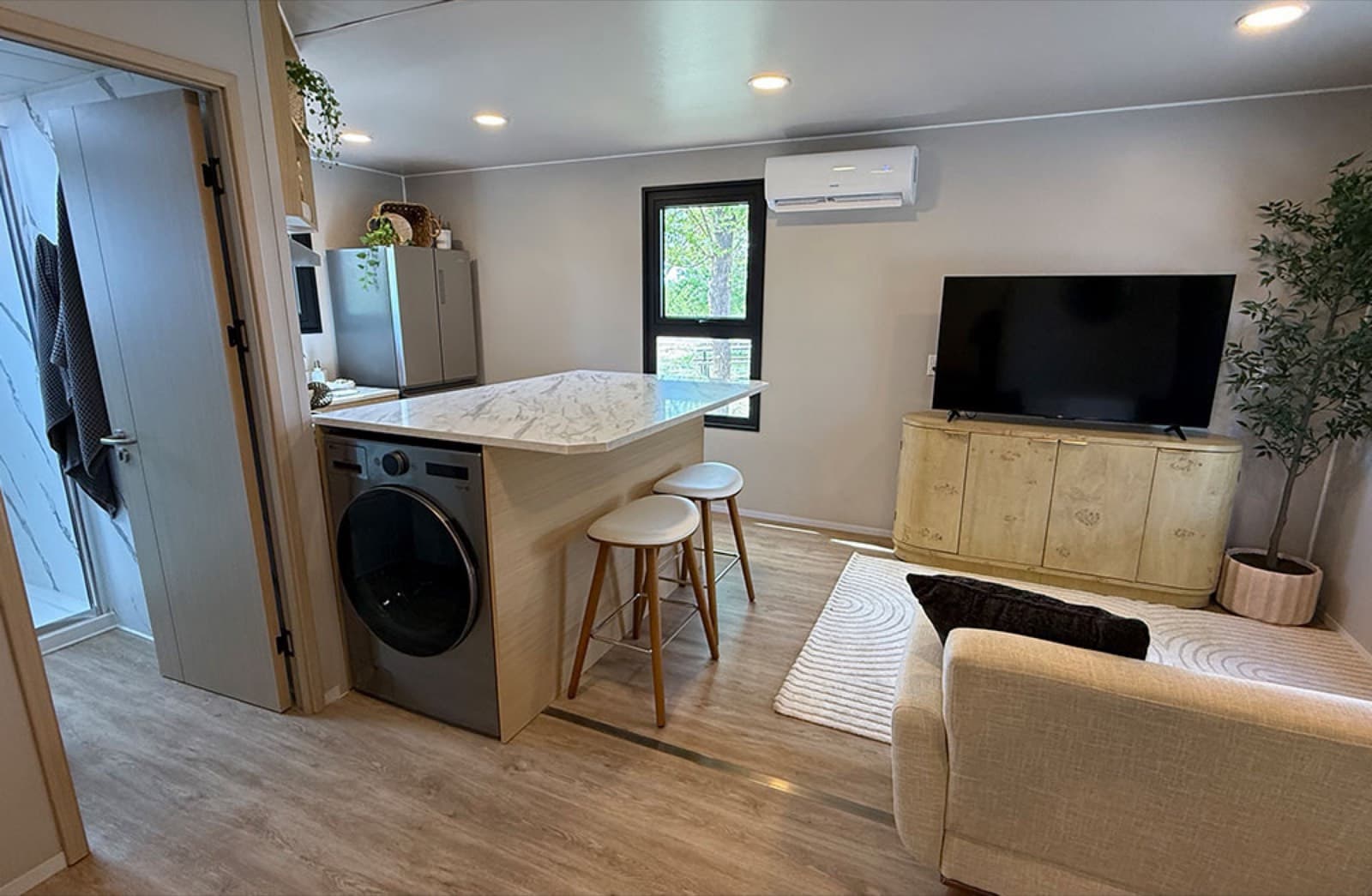 Open living area with kitchen island, washer and dryer, and heat pump in a modular home